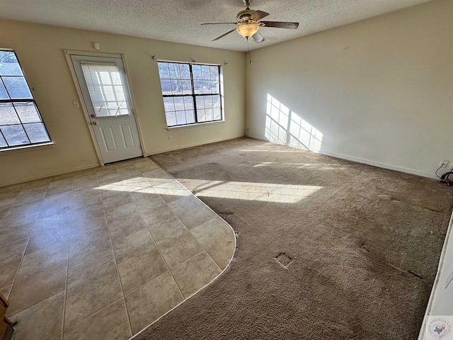 carpeted spare room featuring ceiling fan and a textured ceiling