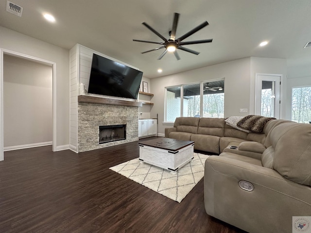 living room featuring baseboards, visible vents, wood finished floors, a stone fireplace, and recessed lighting