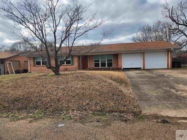 ranch-style home featuring driveway, a garage, and brick siding