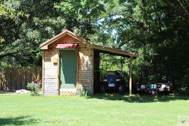 view of outbuilding featuring fence, a carport, and an outbuilding