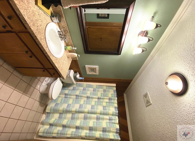 bathroom featuring a textured wall, a sink, and visible vents