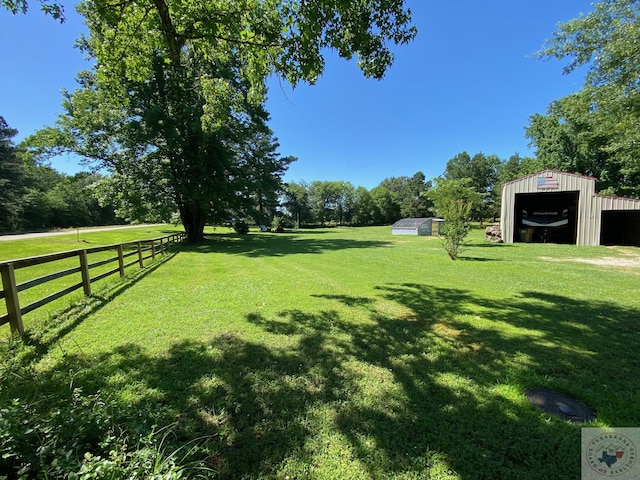 view of yard with a garage, fence, and an outbuilding