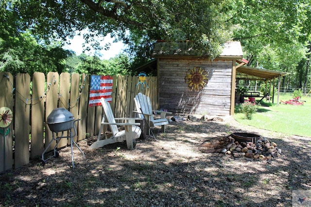 view of yard featuring a storage shed, an outdoor fire pit, a fenced backyard, and an outdoor structure