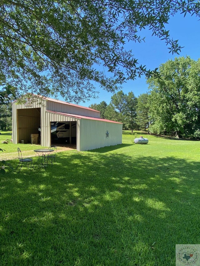 view of yard featuring a garage, a pole building, and an outbuilding