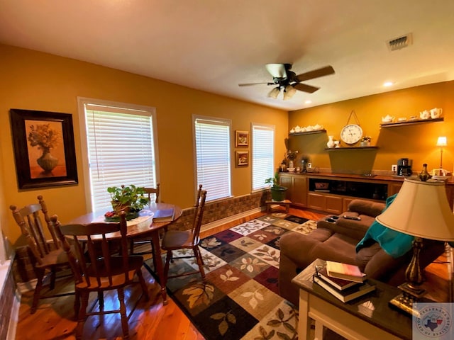 living room featuring wood finished floors, visible vents, and a ceiling fan