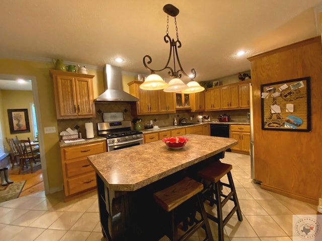 kitchen featuring stainless steel gas range oven, a center island, brown cabinets, wall chimney exhaust hood, and crown molding