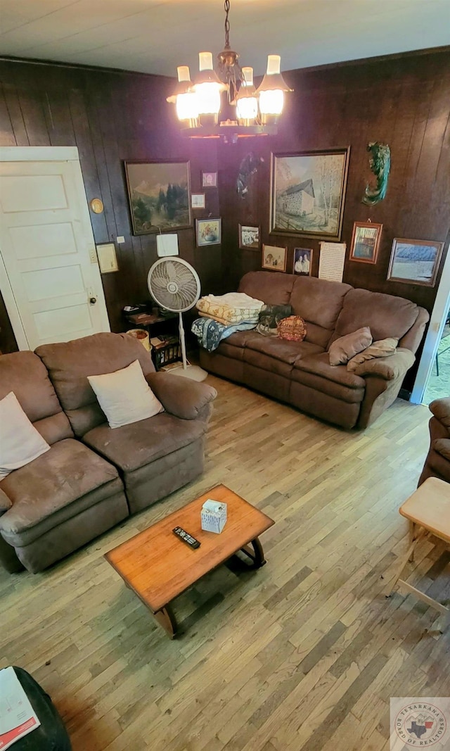 living room with a notable chandelier, hardwood / wood-style flooring, and wooden walls