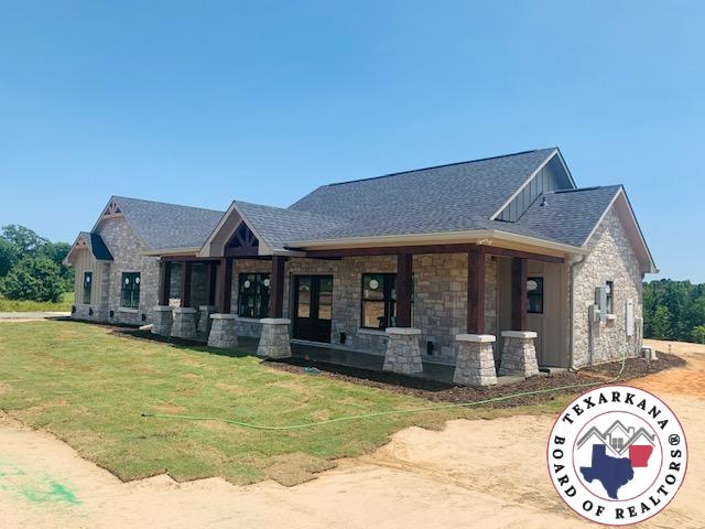 265 Fm 995, Atlanta, TX 75551 - view of front facade featuring board and batten siding, roof with shingles, a front lawn, and stone siding