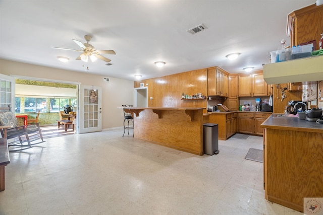 kitchen featuring ceiling fan, a kitchen breakfast bar, sink, and kitchen peninsula