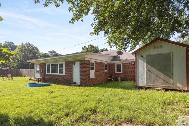 rear view of house with a lawn and a storage shed