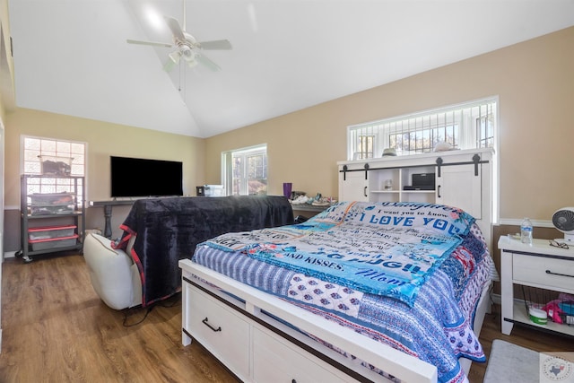 bedroom featuring wood-type flooring, multiple windows, vaulted ceiling, and ceiling fan