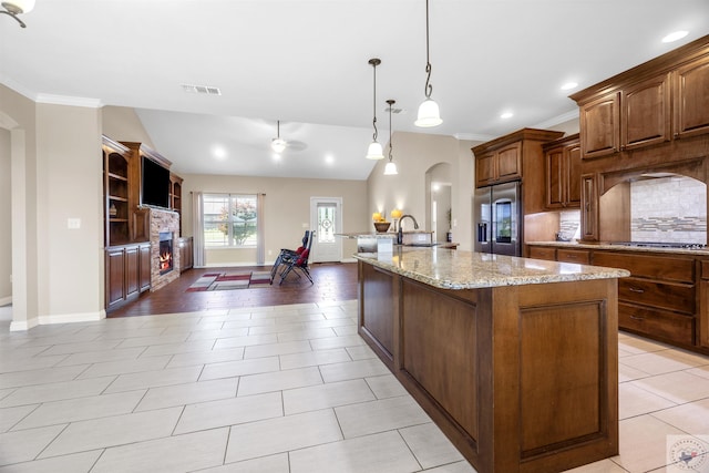 kitchen featuring hanging light fixtures, a large island, sink, a fireplace, and stainless steel appliances