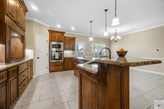 kitchen with appliances with stainless steel finishes, decorative light fixtures, an island with sink, sink, and crown molding