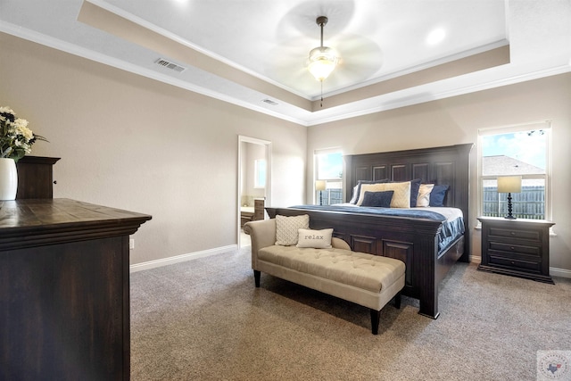 bedroom featuring crown molding, ceiling fan, light colored carpet, a tray ceiling, and ensuite bath