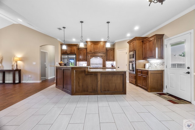 kitchen with crown molding, tasteful backsplash, pendant lighting, stainless steel appliances, and a large island with sink