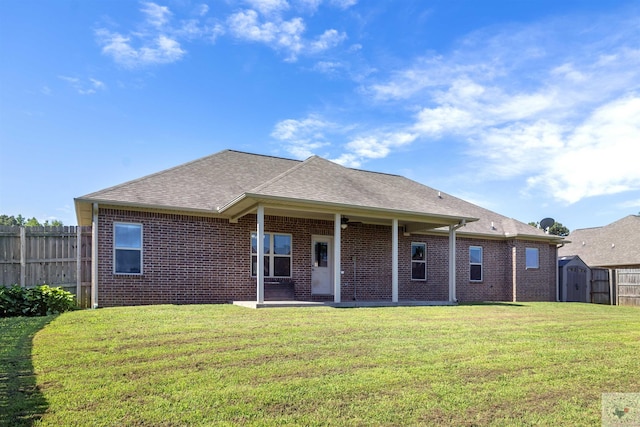 back of property with a storage unit, a patio, and a lawn