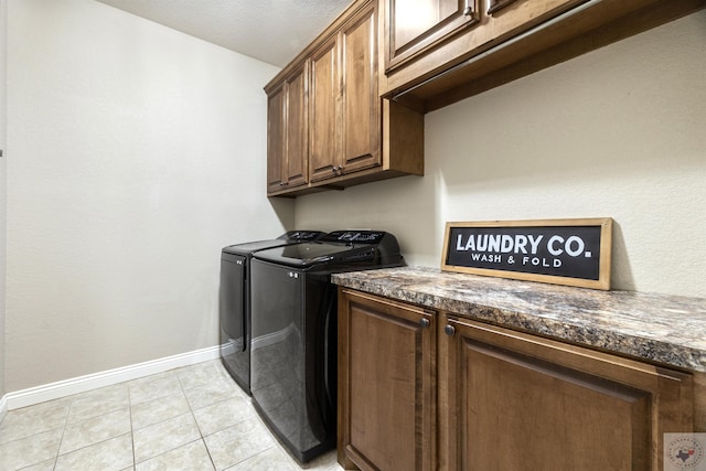 laundry area featuring washer and clothes dryer, light tile patterned floors, and cabinets