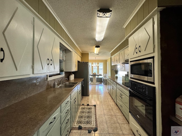 kitchen with crown molding, appliances with stainless steel finishes, a chandelier, light tile patterned floors, and sink