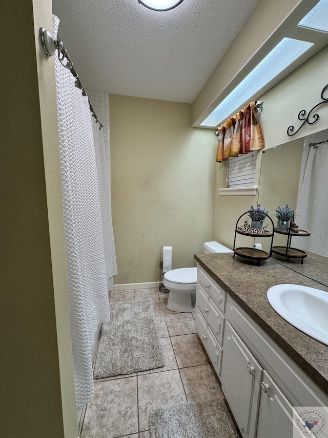 bathroom featuring a textured ceiling, toilet, vanity, and tile patterned flooring