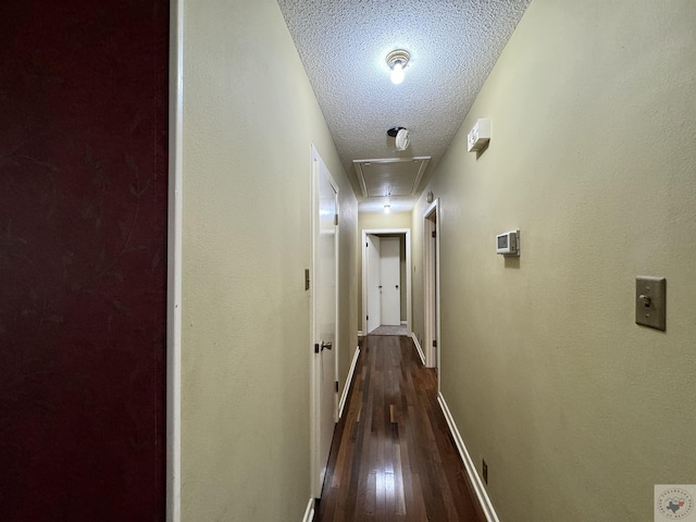 hall with a textured ceiling and dark hardwood / wood-style floors