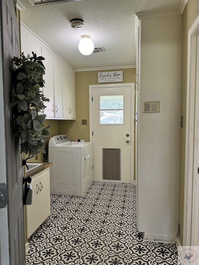 washroom featuring a textured ceiling, ornamental molding, cabinets, and independent washer and dryer