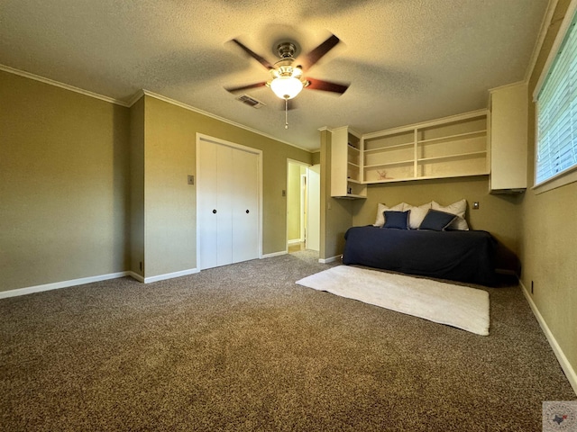 carpeted bedroom featuring a textured ceiling, a closet, ceiling fan, and ornamental molding