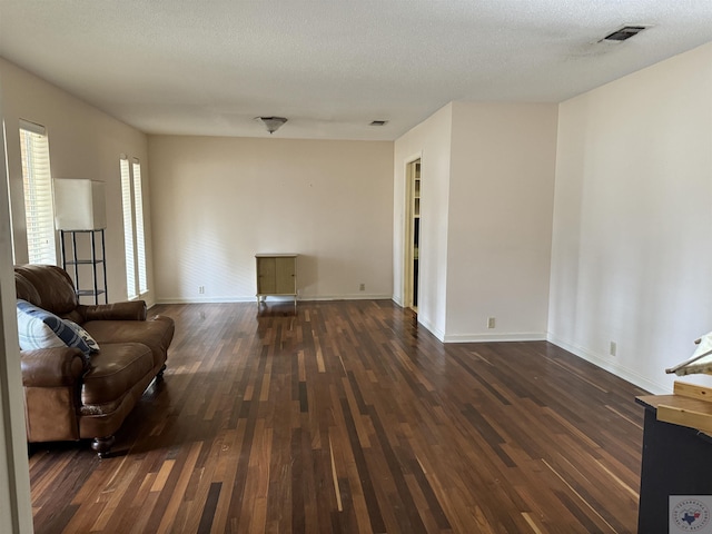 unfurnished living room with a textured ceiling and dark hardwood / wood-style flooring