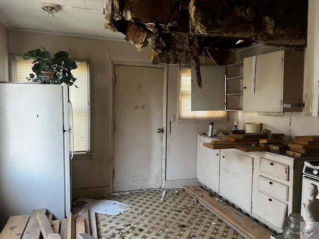 kitchen featuring white cabinets and white fridge