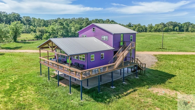 rear view of house featuring a lawn, a deck, and a rural view