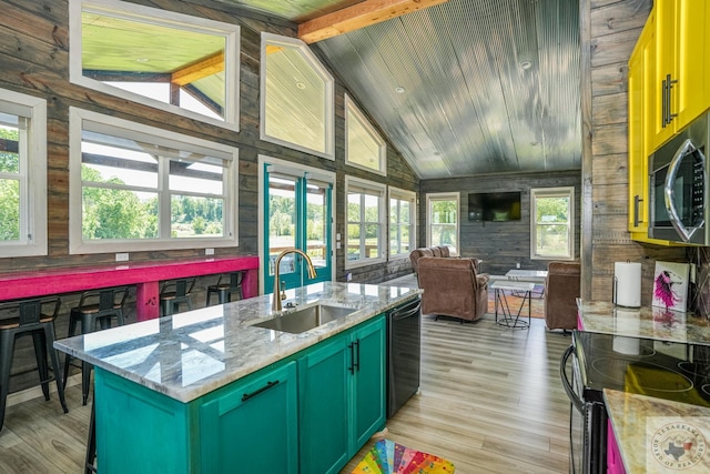 kitchen with dishwasher, sink, lofted ceiling with beams, light stone counters, and light hardwood / wood-style floors