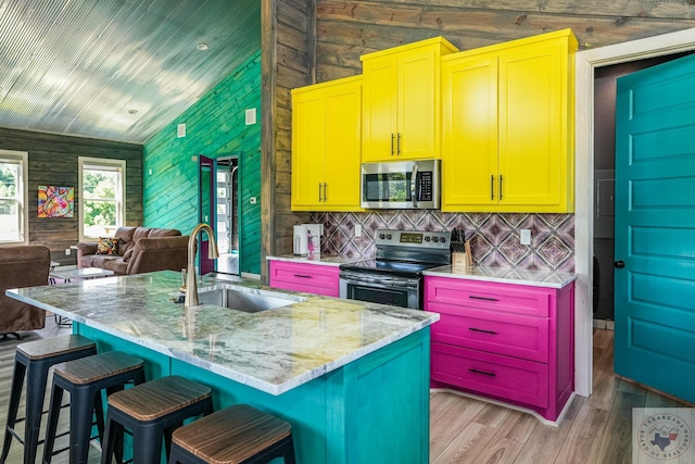 kitchen featuring a kitchen bar, stainless steel appliances, light hardwood / wood-style floors, sink, and a kitchen island with sink