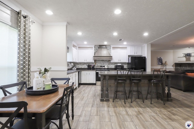 1966 George Thomas Rd, Texarkana, TX 75501 - kitchen with custom exhaust hood, black appliances, a breakfast bar area, backsplash, and dark countertops