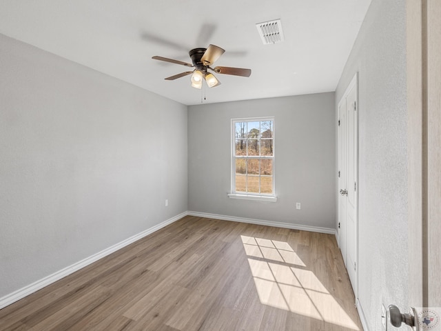 spare room with light wood-style floors, baseboards, visible vents, and a ceiling fan