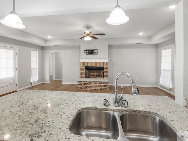 kitchen with light stone counters, a fireplace, a sink, and decorative light fixtures