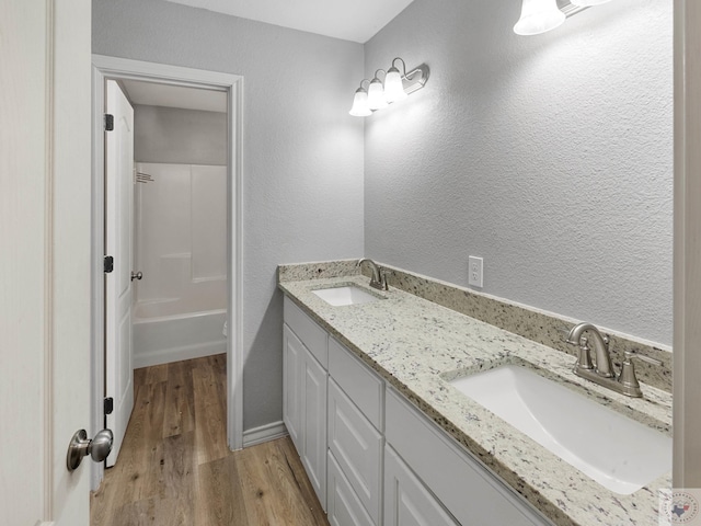 full bath with double vanity, toilet, a sink, and wood finished floors