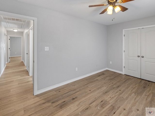 unfurnished bedroom featuring light wood-style flooring, visible vents, baseboards, a closet, and attic access