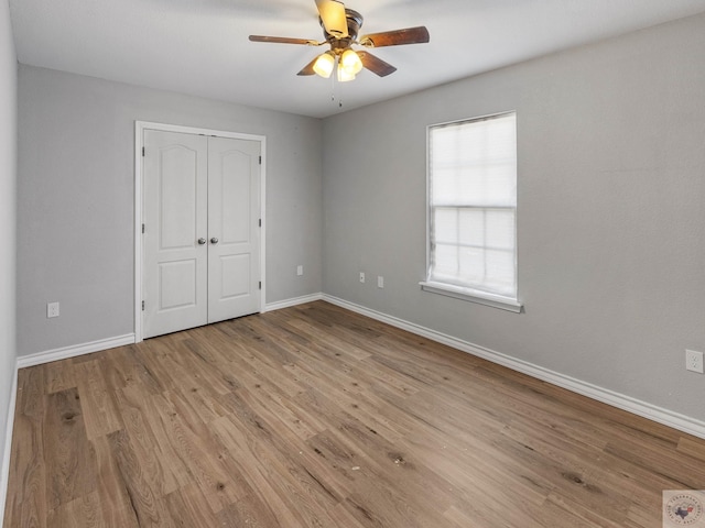 unfurnished bedroom featuring a ceiling fan, a closet, baseboards, and light wood finished floors