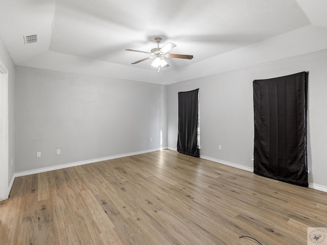 spare room with visible vents, light wood finished floors, a ceiling fan, and baseboards