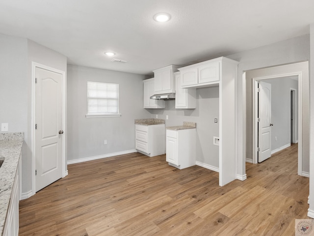 kitchen with light wood finished floors, baseboards, light stone counters, under cabinet range hood, and white cabinetry