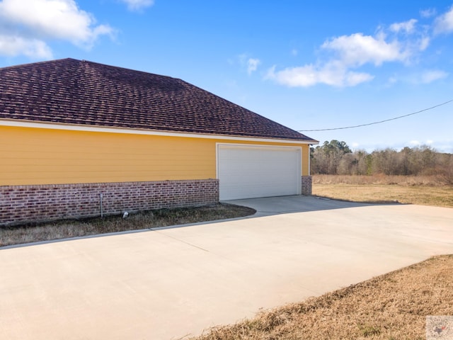 view of side of home with a garage, an outbuilding, and brick siding