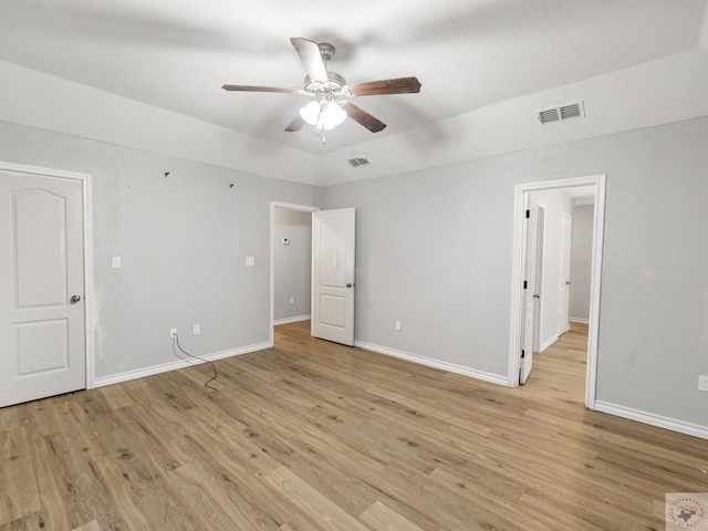 empty room featuring light wood-style flooring, visible vents, and baseboards