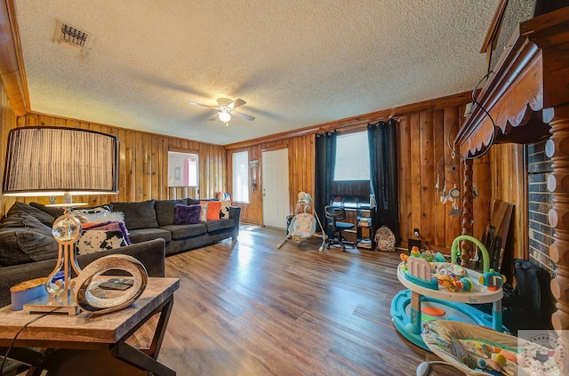 living room with wood walls, hardwood / wood-style floors, a textured ceiling, and ceiling fan