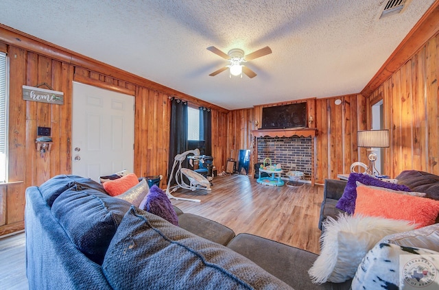 living room featuring wood-type flooring, a textured ceiling, wood walls, and ceiling fan