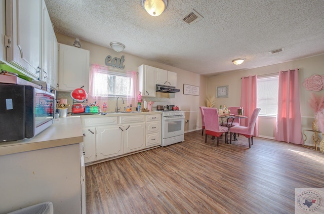 kitchen featuring sink, white range with gas cooktop, white cabinets, and a wealth of natural light