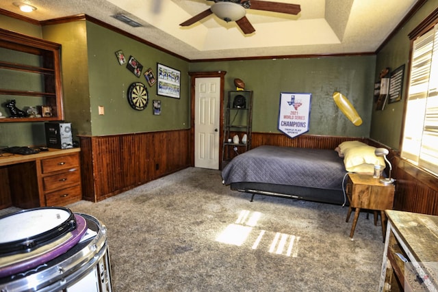 carpeted bedroom featuring ceiling fan, multiple windows, a tray ceiling, and ornamental molding