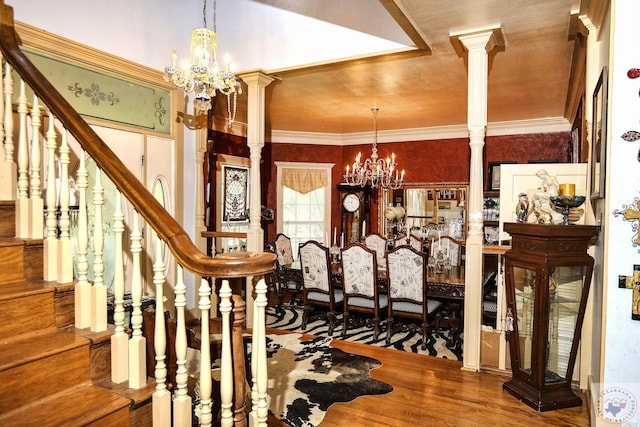 dining room with a notable chandelier, ornate columns, ornamental molding, and wood-type flooring