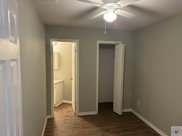 unfurnished bedroom featuring wood-type flooring, a closet, ceiling fan, and a walk in closet