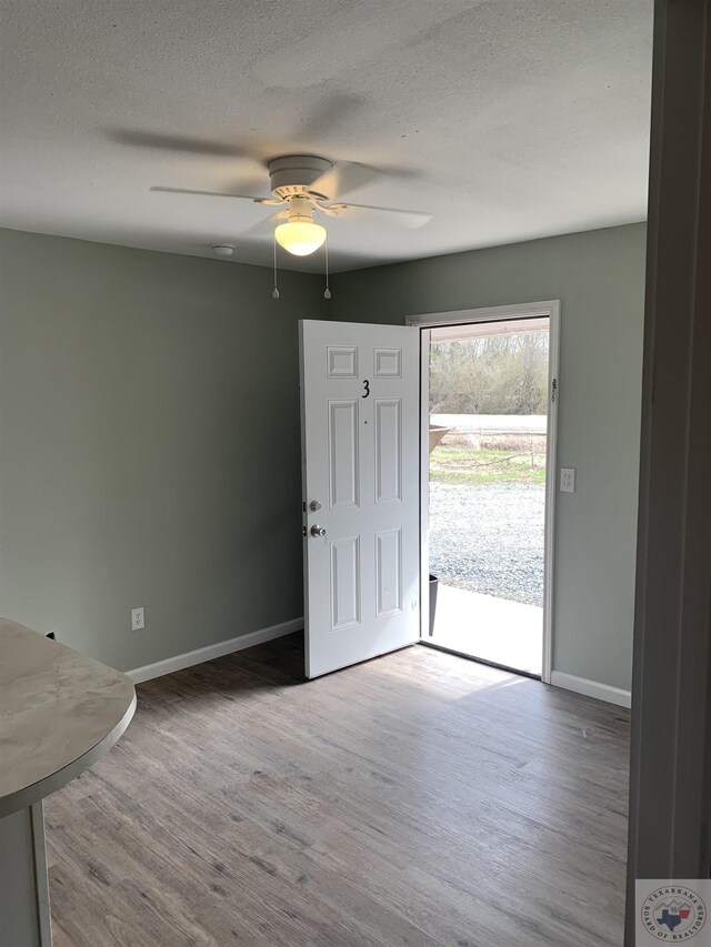 foyer entrance with ceiling fan, a textured ceiling, and wood-type flooring