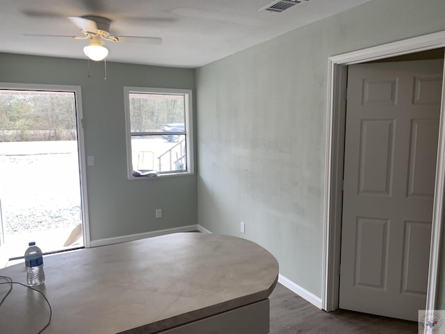 unfurnished dining area featuring ceiling fan and dark wood-type flooring