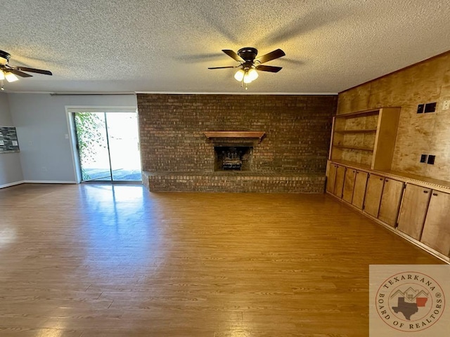 unfurnished living room with a brick fireplace, a textured ceiling, ceiling fan, and light hardwood / wood-style floors